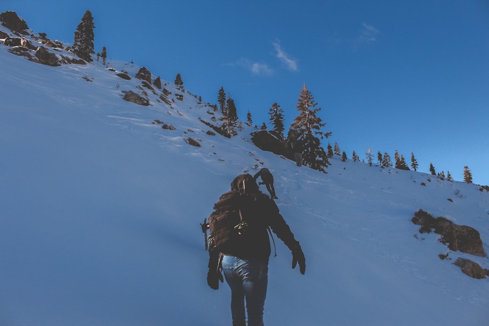 person walking on snow covered hill during day