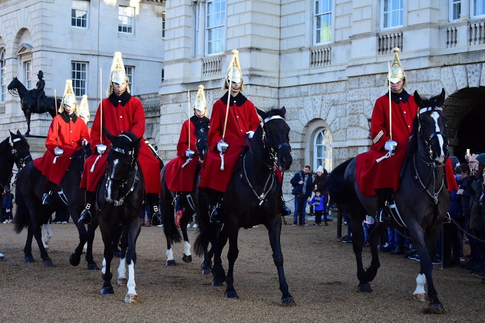 homem vestindo casaco vermelho montando cavalos durante o dia