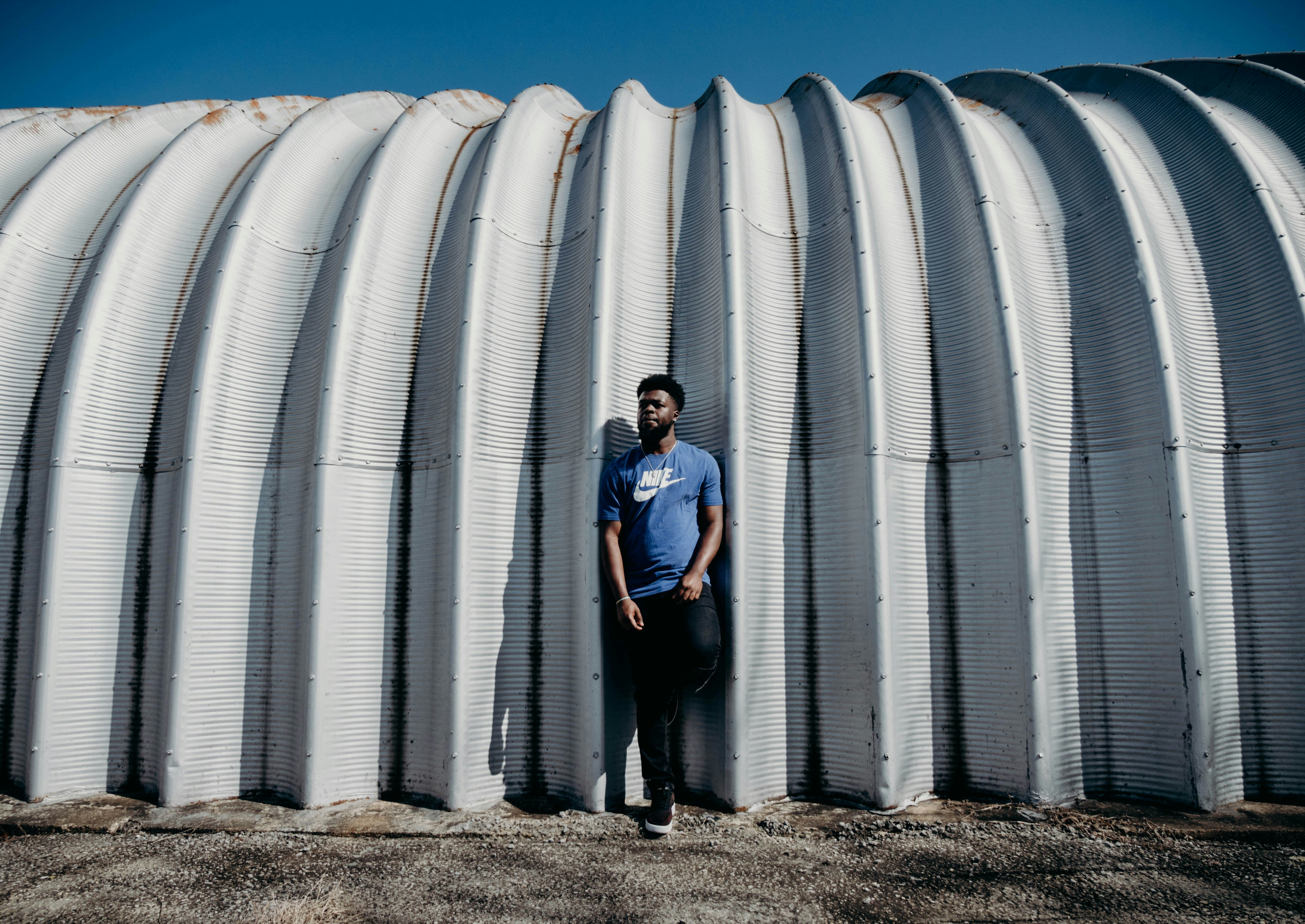 man in blue t-shirt standing on white ribbed arch estabdlidhment