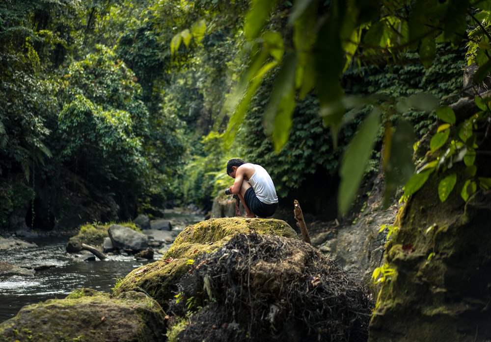 man sitting beside river