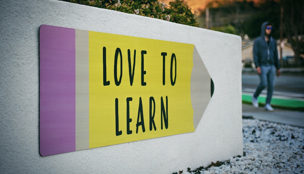 love to learn pencil signage on wall near walking man