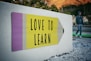 love to learn pencil signage on wall near walking man