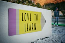 love to learn pencil signage on wall near walking man