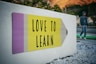love to learn pencil signage on wall near walking man