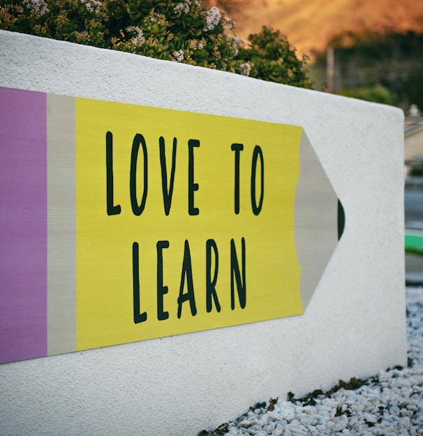 love to learn pencil signage on wall near walking man