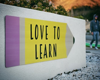 love to learn pencil signage on wall near walking man