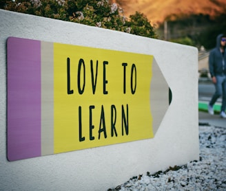 love to learn pencil signage on wall near walking man