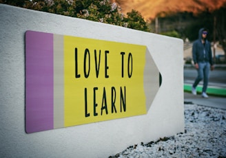 love to learn pencil signage on wall near walking man