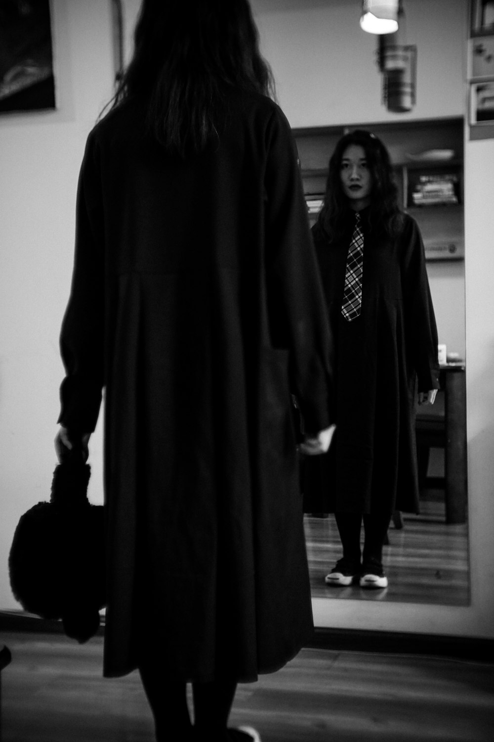 woman wearing black coat facing mirror