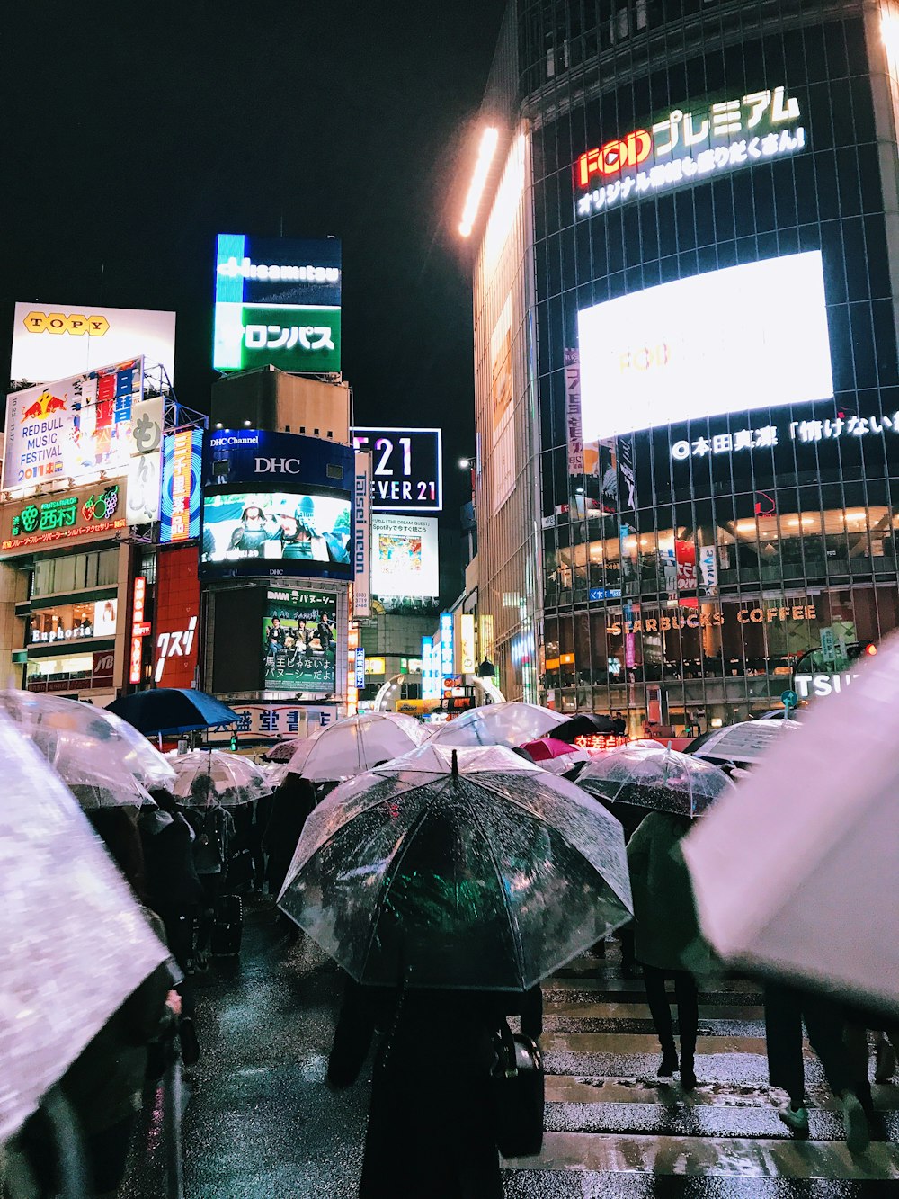 people with umbrellas walking near buildings during night