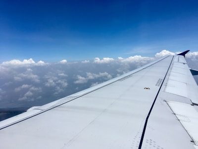 A cozy airplane cabin seat with a window view of clouds below.
