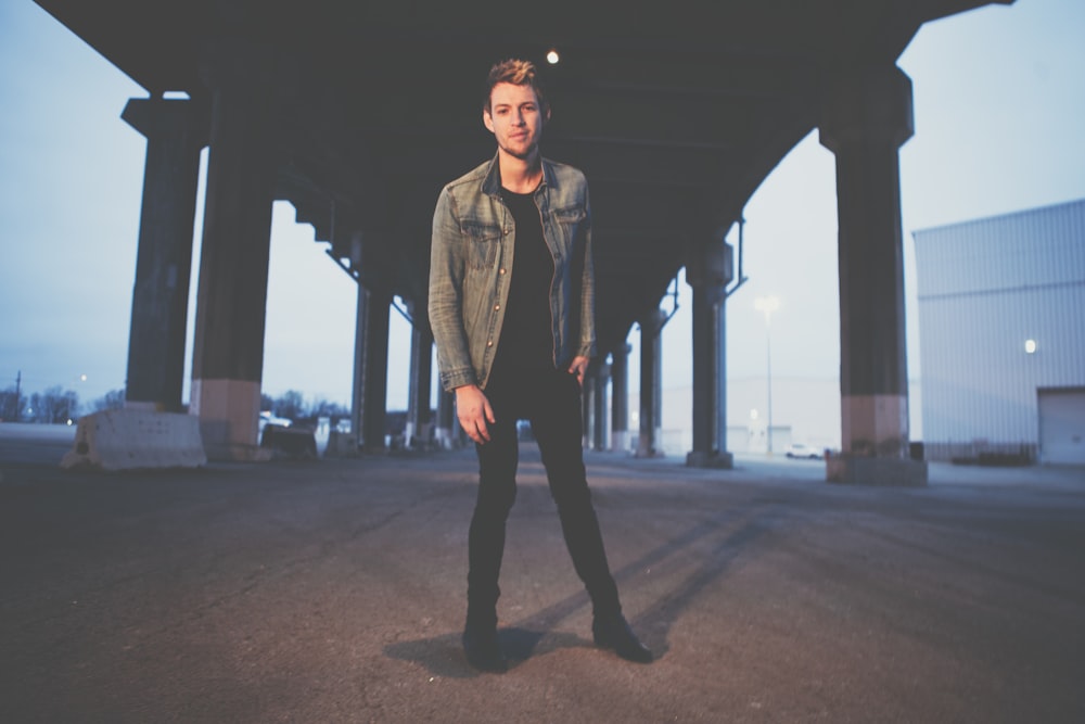 man standing under concrete bridge