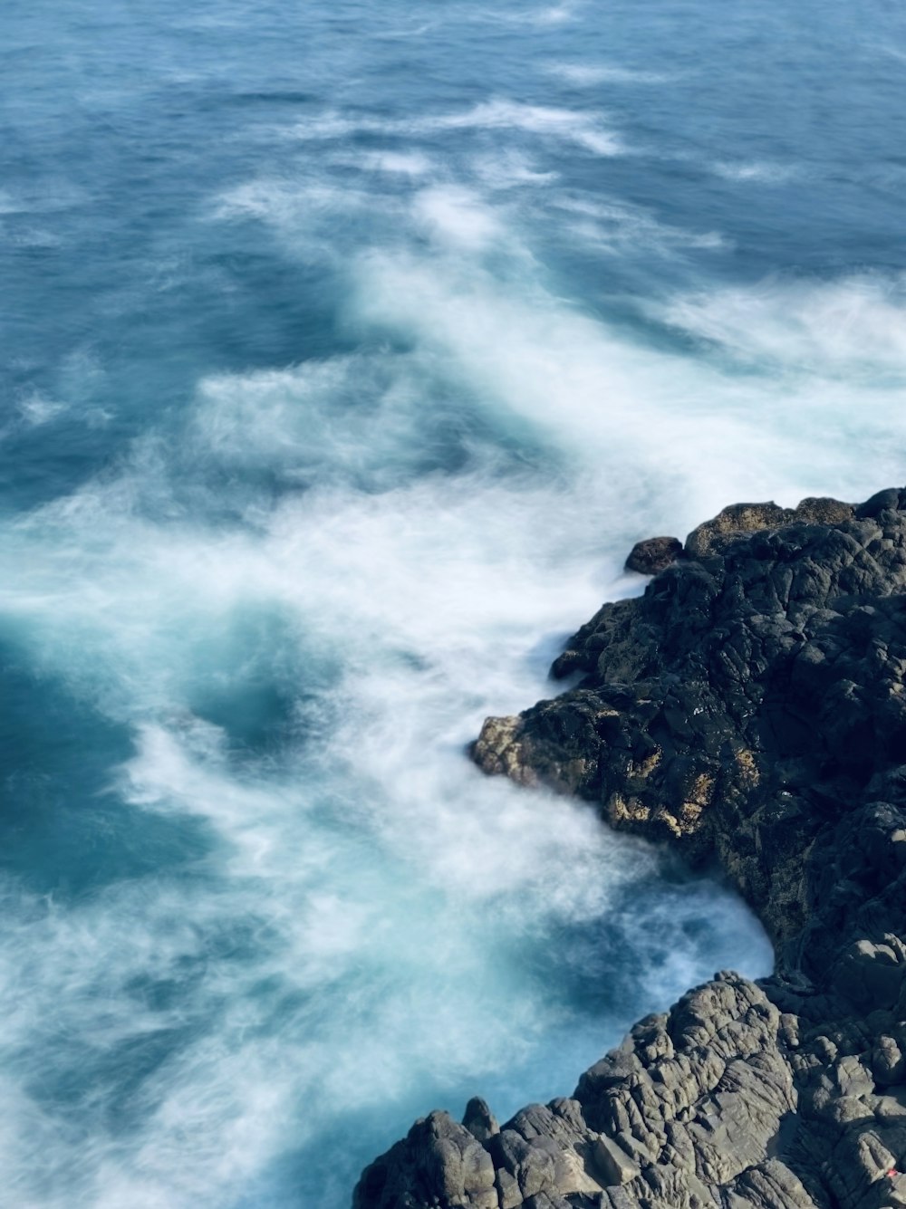 blue sea waves in black stones