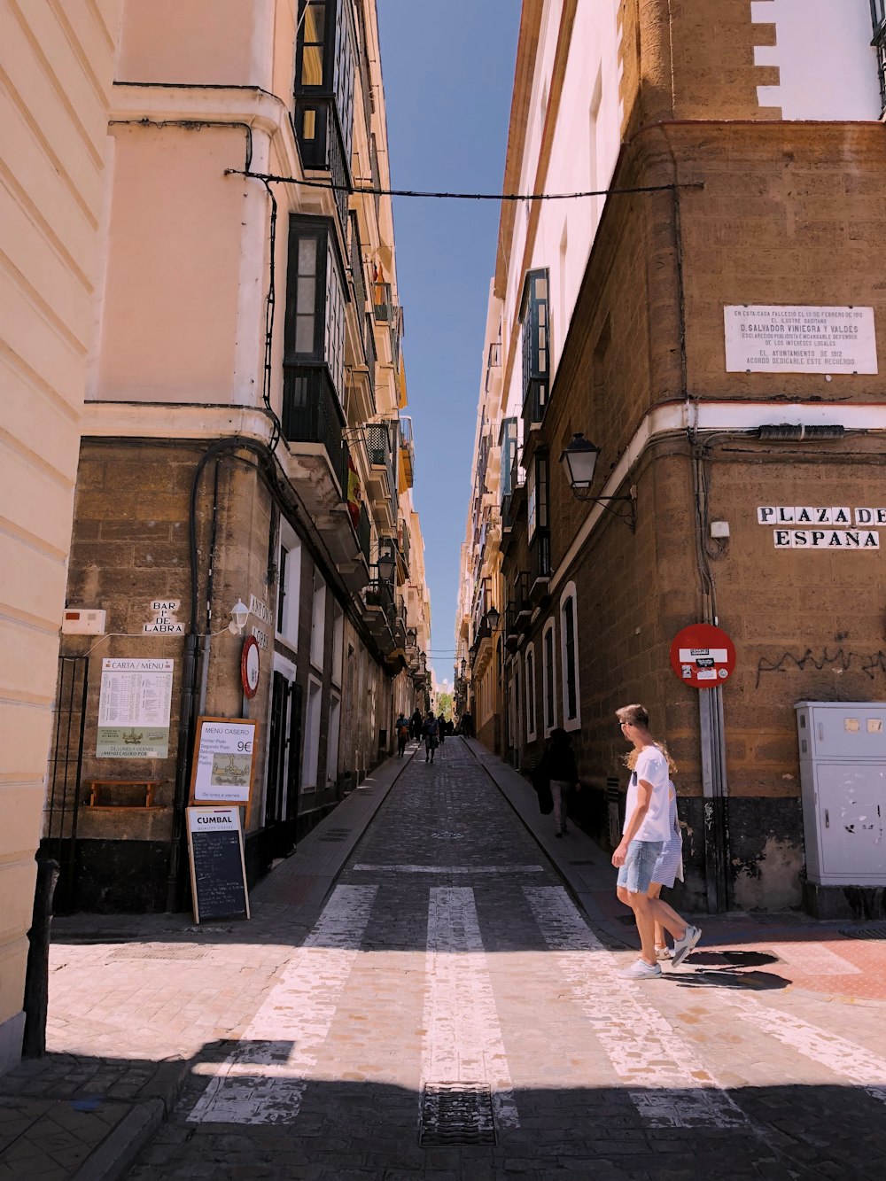 man walking near two brown concrete buildings