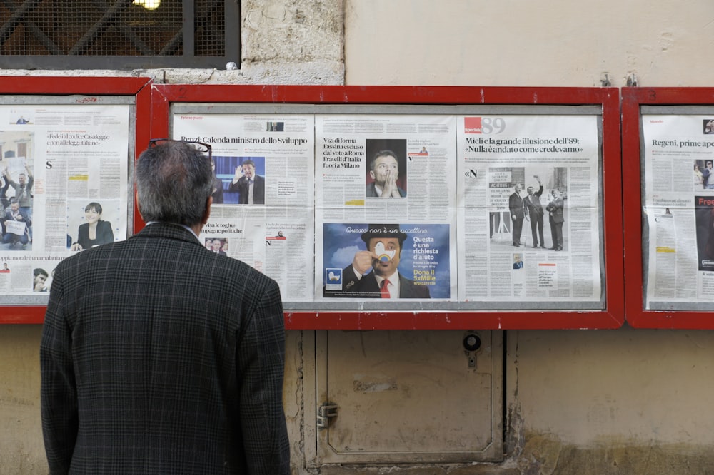 Mann liest Zeitung am Schwarzen Brett