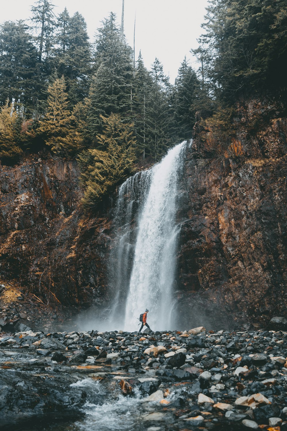 Frau geht in der Nähe des Wasserfalls spazieren