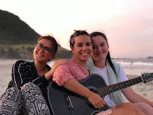 A group of musicians sharing smiles and tunes during an outdoor folk session at sunset.