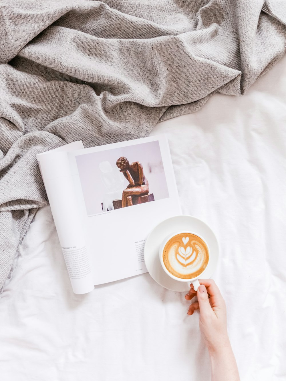 latte and magazine on white comforter