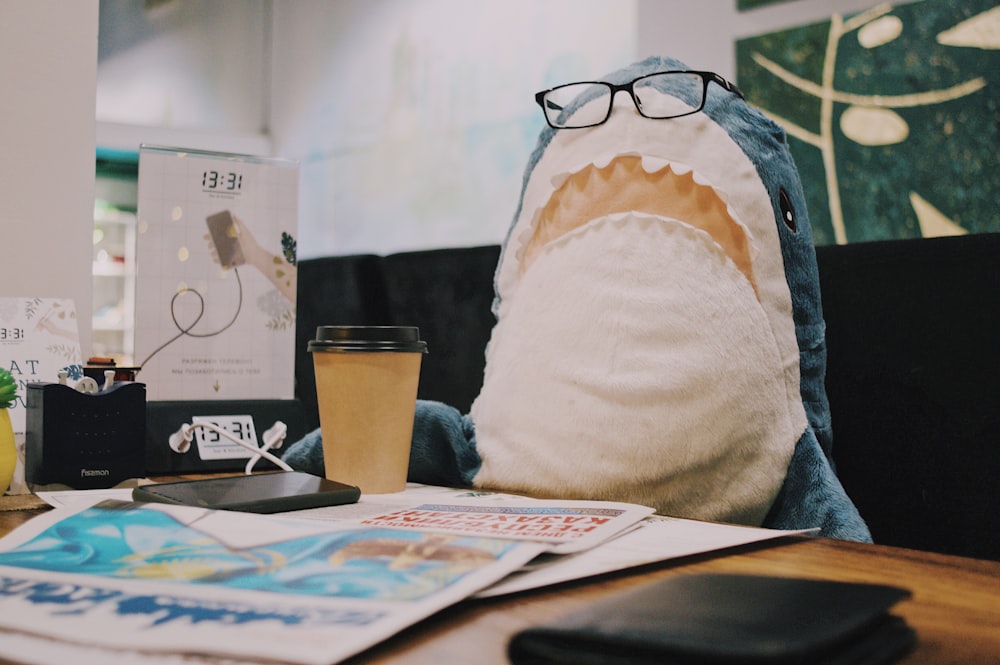 white and blue shark plush toy near table