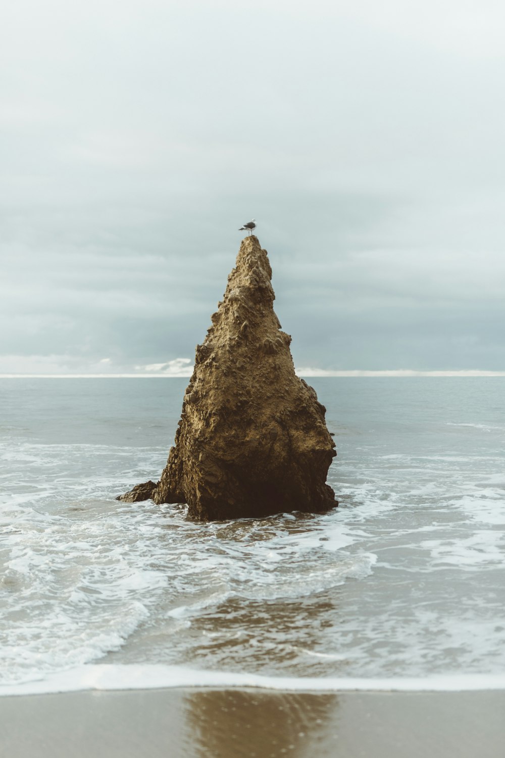 brown rock surrounded by salt water during daytime