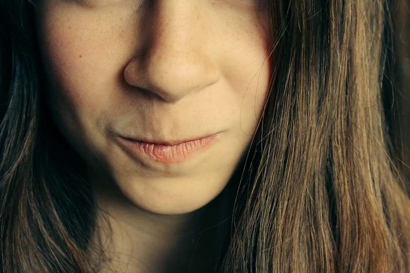 Close-up portrait of a woman with a sly smile, hinting at deception.