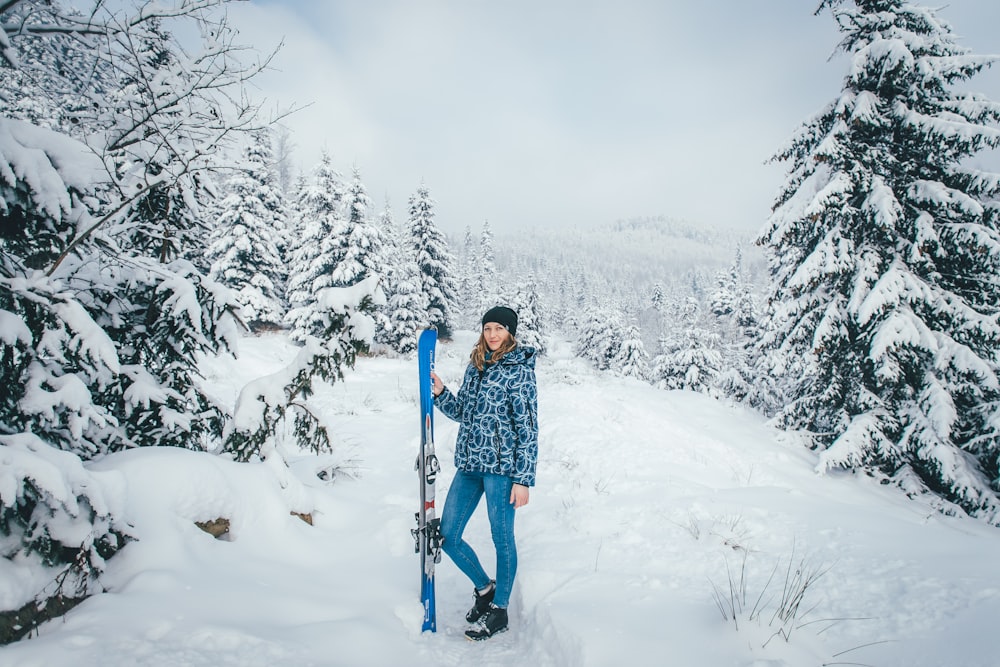 Mulher em pé na montanha de neve segurando esquis de neve