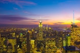 A vibrant cityscape view from a hotel balcony at sunset.