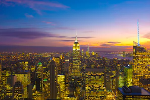 A vibrant city skyline at sunset with glowing lights and bustling streets.