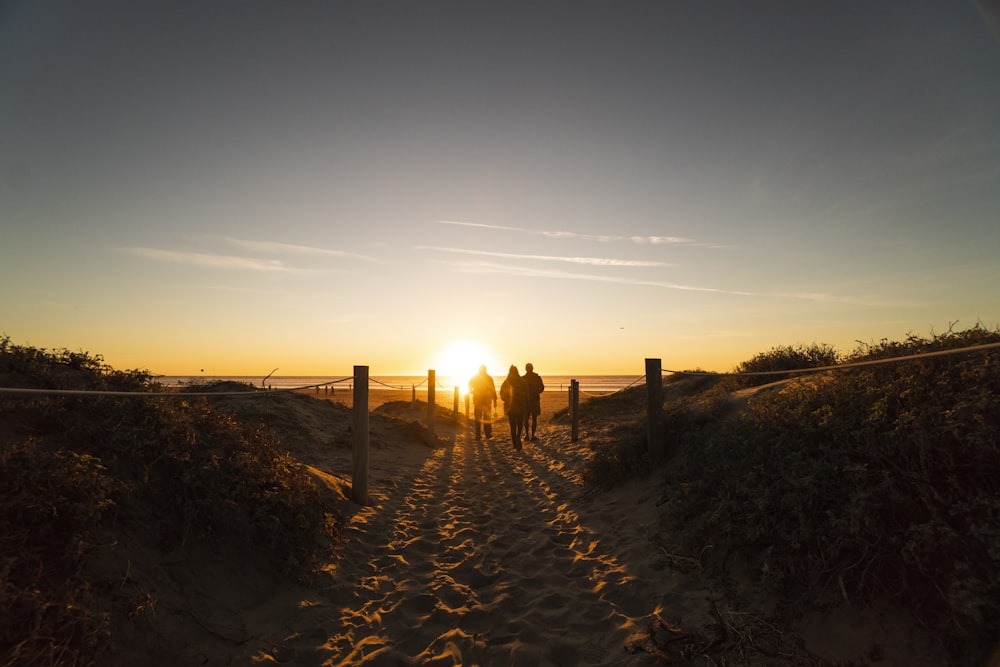 três pessoas caminhando em dunas de areia perto da praia