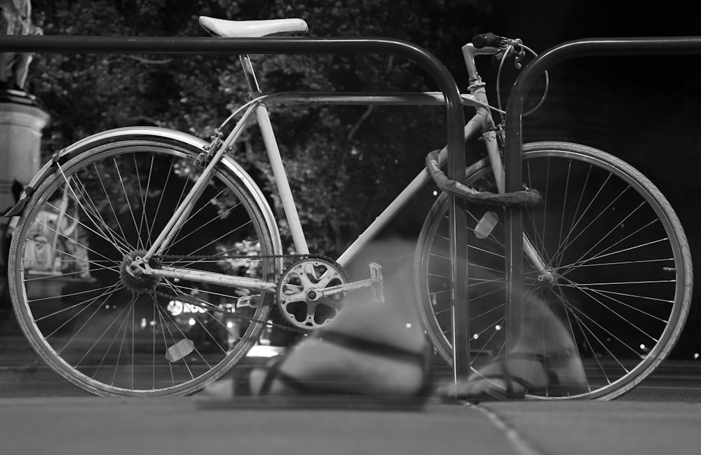 white road bike chained on steel post