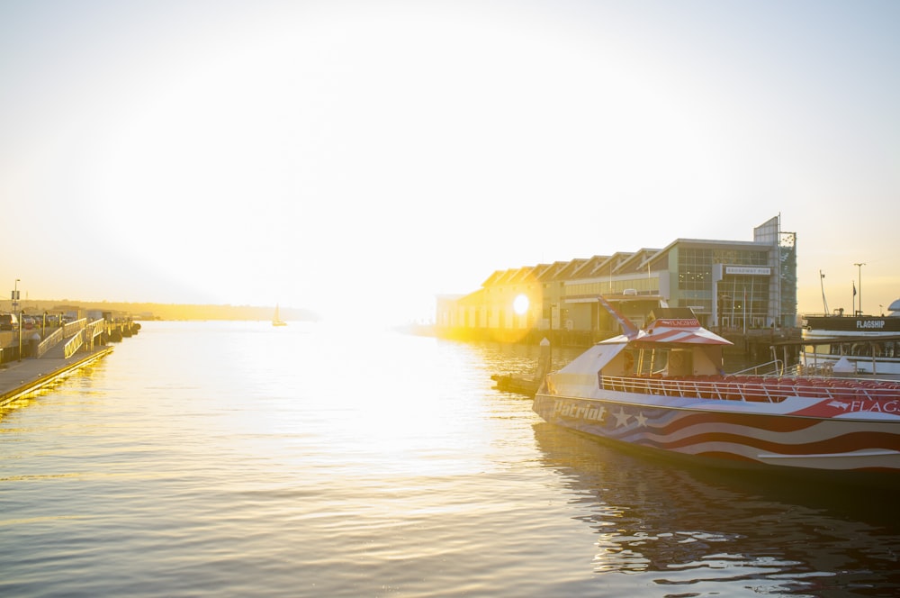 dock white, red, and blue boat during golden hour