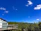A cozy modular park home with a small garden and a bright blue sky overhead.