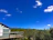 A cozy modular park home with a small garden and a bright blue sky overhead.