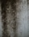 A textured surface displaying dark, uneven patches and speckles, resembling mold or dirt accumulation on a lighter concrete wall.