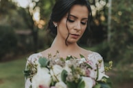 woman with white dress holding bouquet of roses