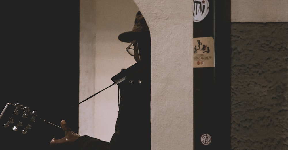 person holding guitar leaning on wall