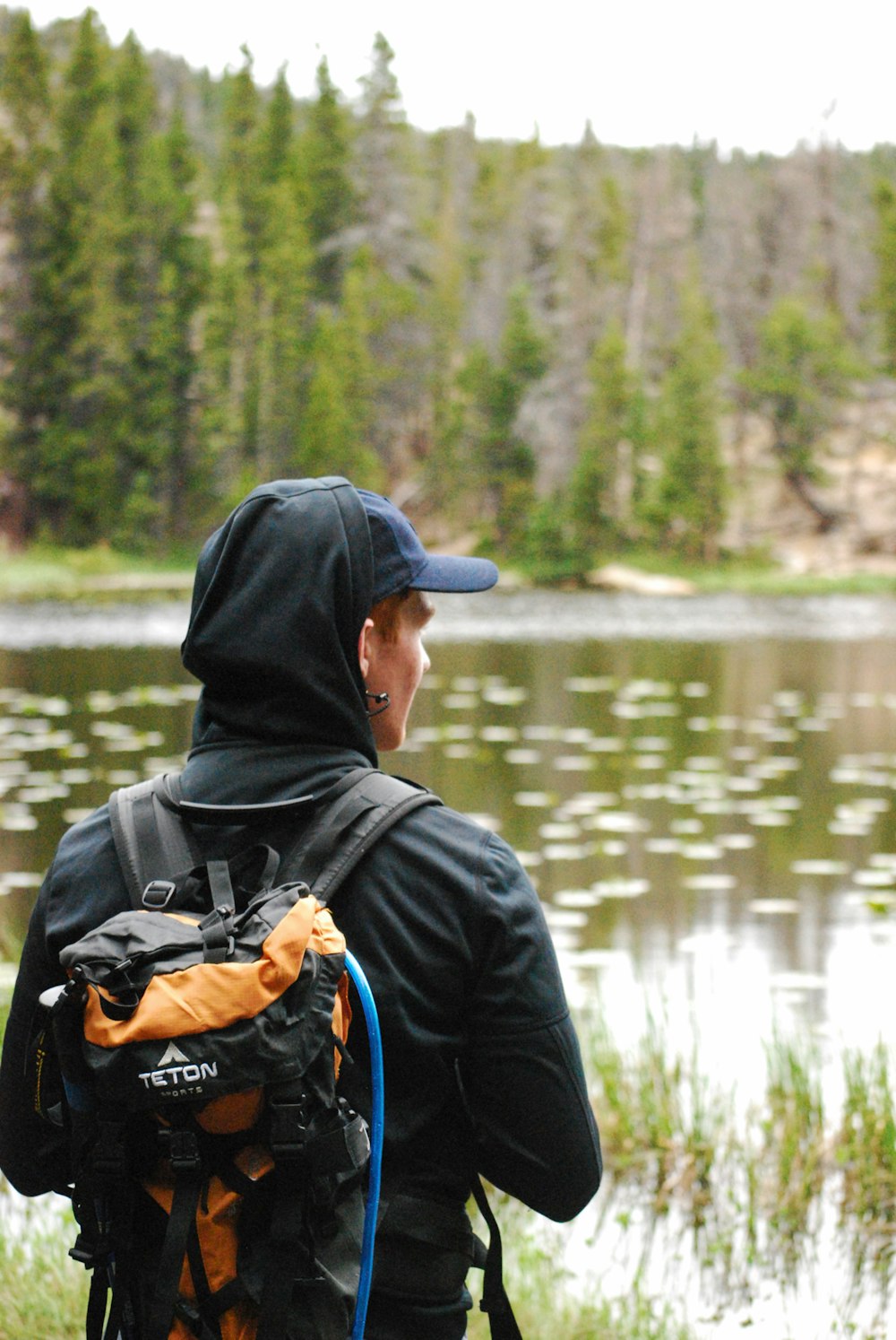 person wearing black jacket and orange and black backpack