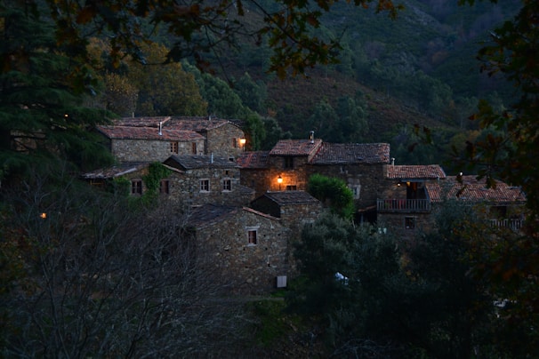Cozy countryside guesthouse with warm lights glowing at dusk, surrounded by gentle hills.