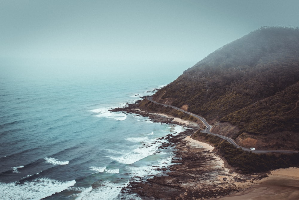 aerial photography of mountains beside road and sea