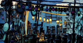 A marketplace stall displaying an array of decorative lanterns, mirrors, and vases. The scene is crowded with various ornamented items, with hanging colored lanterns illuminating the area in warm and cool tones. There are intricate designs and patterns evident in the items, creating an eclectic and vibrant atmosphere.
