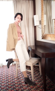 A casual yet polished outfit featuring a cozy knit sweater and tailored pants, styled on a wooden chair near a sunlit window.
