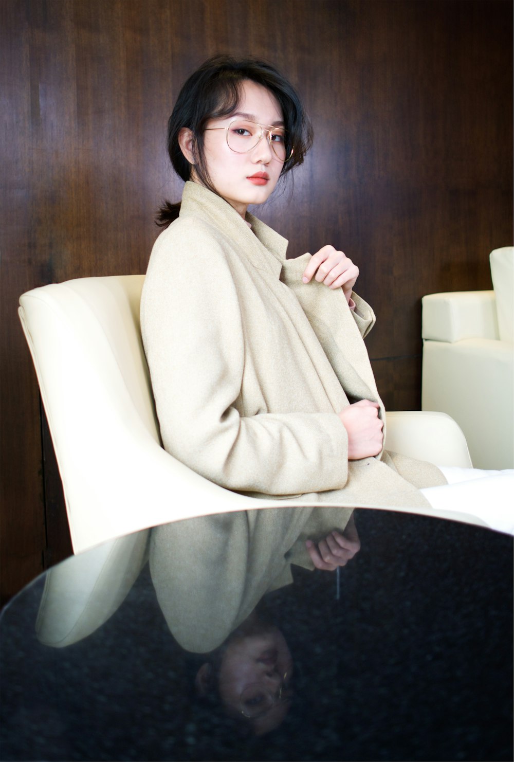 소파 의자에 앉아 갈색 코트를 입은 여성의 선택적 초점 사진