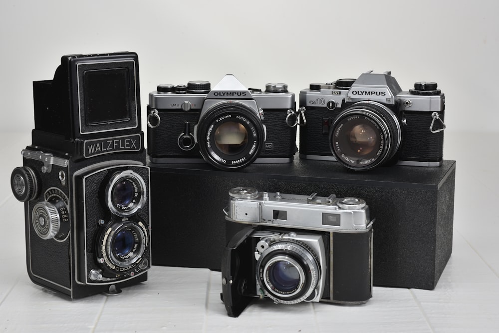 four vintage gray cameras on white surface