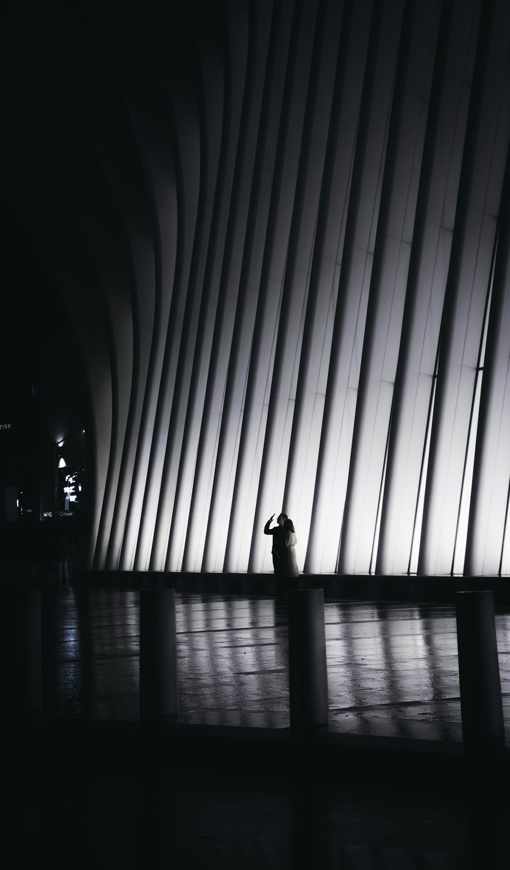 grayscale photo of man standing near vertical lines