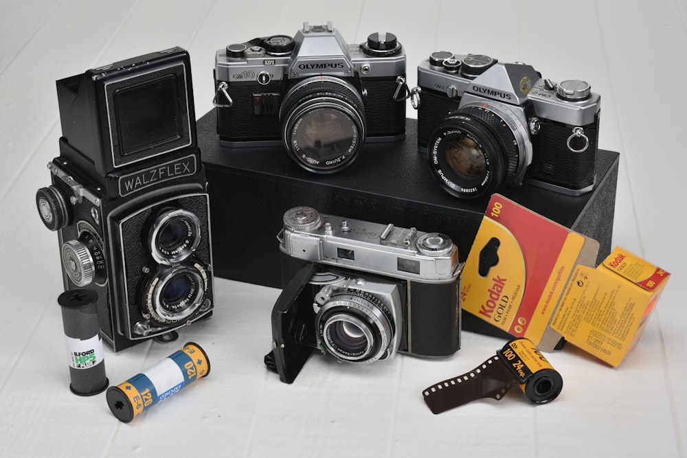 four gray-and-black classic cameras with film rolls