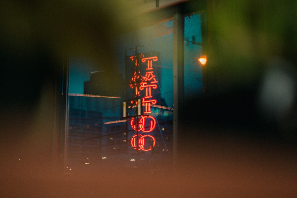 selective focus photography of red tattoo neon signage