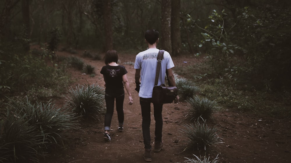 man and woman walking going on forest
