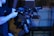 A person is holding a professional video camera rig with various mounted components, including a lens and monitor. The setup is complex and equipped for advanced video production. The background is blurred, suggesting a focus on the equipment.