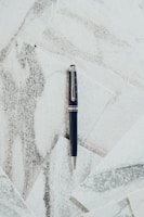 Close-up of a sleek black padbergpen with silver accents resting on a wooden desk.