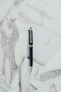 Close-up of a sleek, matte black executive pen resting on a textured leather desk pad.